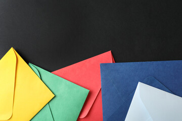 Colorful paper envelopes on black background, flat lay