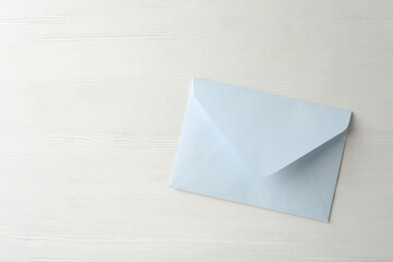 Light paper envelope on white wooden table, top view. Space for text