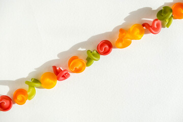 Multicolored pasta lie in line on a white background. Top view. Copy, empty space for text
