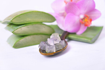 chopped small pieces of aloe vera in a wooden spoon, orchid and pieces of aloe vera