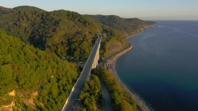 large bridge for motorway across sea, aerial view of drone slide turn, beautiful design of the automotive bridge in sea. Travel. Flying Over Bridge as Cars Pass. Sochi, Russia