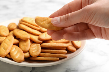 Woman taking delicious cracker from plate, closeup