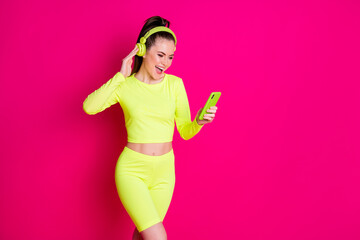 Photo of slim crazy girl listen headset volume music use smartphone sport wear isolated on pink bright color background