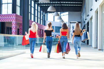 Back view young girlfriends are walking in the mall