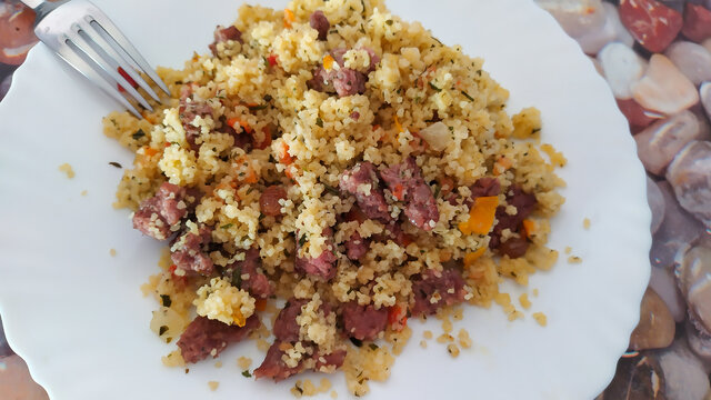 Top view of tabbule with meat on a white plate and fork