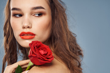 Fototapeta na wymiar woman with a rose in her hands naked shoulders evening makeup red lips