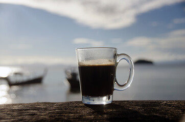 Close up Coffee cup on old wood table and view of tropical beach