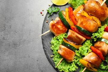 Delicious chicken shish kebabs with vegetables on grey table, top view. Space for text