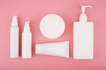 Set of white unbranded cosmetic products for skin care on pink background flat lay