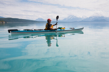 Man sea kayaking calm waters of an inlet in a national park.