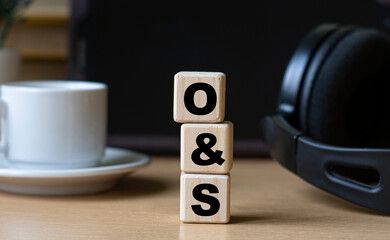 O&S -word on cubes on the background of the tablet, headphones and a white cup