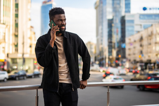 African American man smiling and talking on the phone while walking down the street