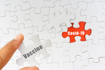 Hand holding jigsaw puzzle with text VACCINE and COVID-19. Covid-19 and Coronavirus concept