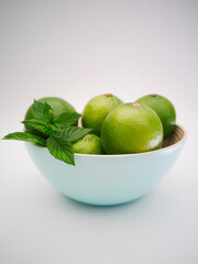 Colorful juicy limes in the bowl on the white background.