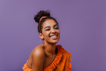 Good-humoured black girl funny smiling in studio. Ecstatic young woman in summer blouse chilling on purple background.