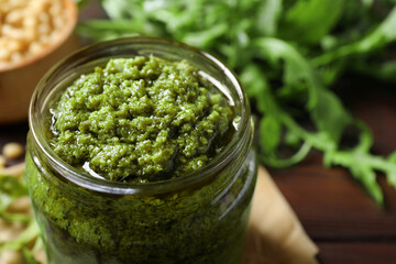 Jar of tasty arugula pesto on table, closeup