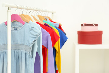 Obraz premium Different child's clothes hanging on rack indoors. Space for text