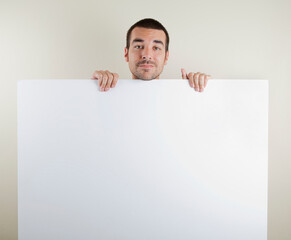 Studio photo of smiling man in his 30s holding a large blank paper sign wearing a red t shirt. Isolated on bright background.
