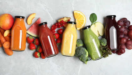 Bottles of delicious juices and fresh fruits on marble table, flat lay