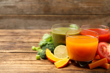 Delicious vegetable juices and fresh ingredients on wooden table. Space for text