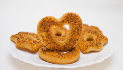 Curly Biscuits with poppy seeds on a white plate on a white background