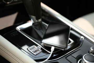 Mobile phone with charging cable in car, closeup