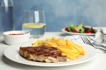Grilled steak with French fries on white table
