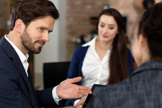 Closeup portrait of businessman talking to colleagues, using tablet.