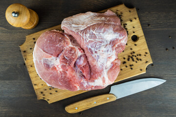 Juicy raw piece of meat with a knife and pepper on a wooden Board. The view from the top.