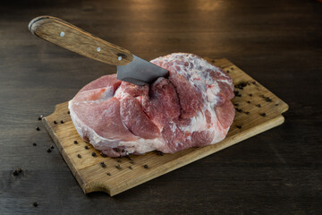 Juicy raw piece of meat with a knife and pepper on a wooden Board. The view from the top.