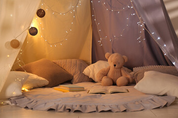 Play tent with books, pillows and Teddy bear. Modern children's room interior © New Africa