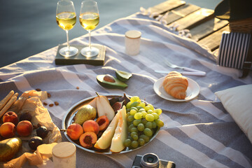 Picnic blanket with delicious food and wine on pier