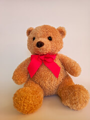 
soft toy, brown teddy bear with a red bow around his neck on a white background