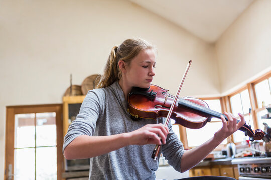 13 year old girl playing violin at home