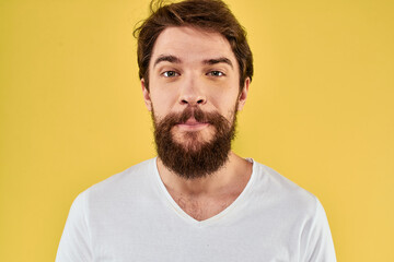 Obraz premium A man in a white t-shirt gestures with his hands lifestyle cropped view yellow background more fun