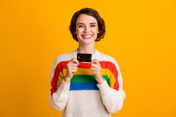 Photo of charming lady hold demonstrate credit card toothy smile wear striped pullover isolated...