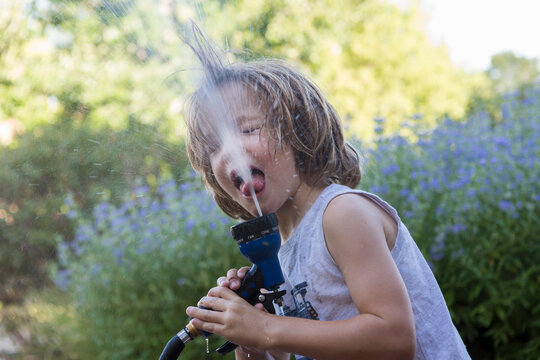 5 year old boy drinking from water hose