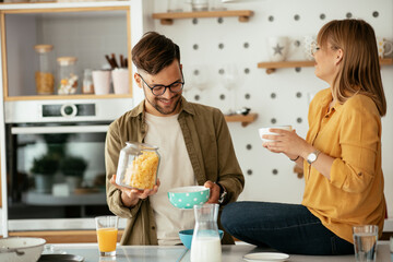 Young couple eating breakfast at home. Loving couple enjoying in the kitchen
