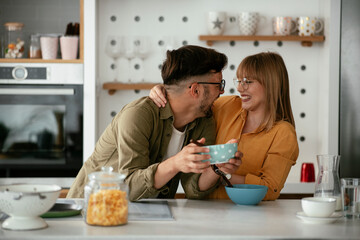 Young couple eating breakfast at home. Loving couple enjoying in the kitchen