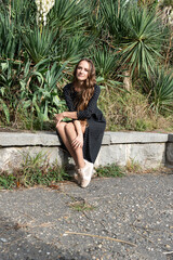 Portrait of a young woman who is sitting on a stone bench.