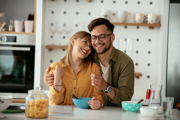 Young couple eating breakfast at home. Loving couple enjoying in the kitchen