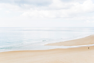 Beach scene with soft light. Lonely woman silhouette walking on a sand beach in winter, France.