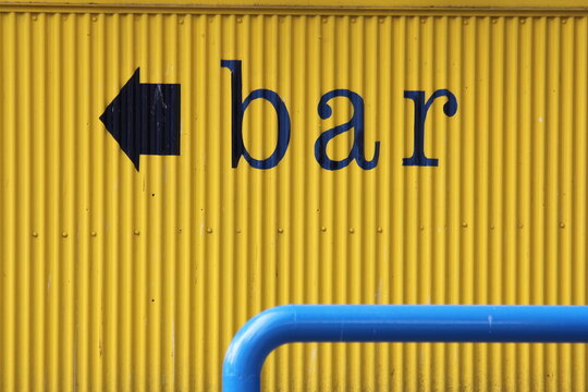 Arrow And Blue Metal Bar On A Bright Yellow Corrugated Steel Background With Lower Case Letters Spelling BAR