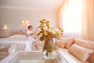 A pretty young girl. Bride's boudoir morning. Sitting on the bed with a bouquet of flowers