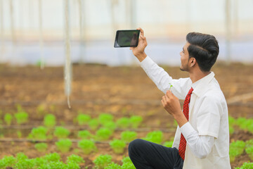 Technology and people concept, Young indian agronomist take selfie in tablet or smartphone at greenhouse