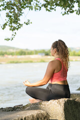Fototapeta na wymiar Girl or woman practicing yoga outdoors near a river