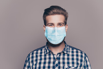 Photo portrait of handsome young man wearing blue face mask isolatet on gray wall