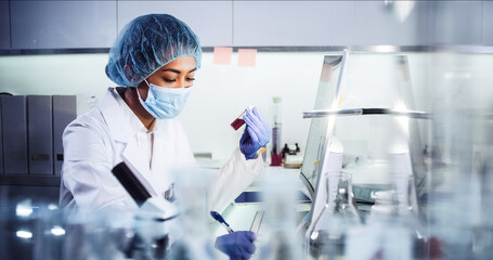 Asian female doctor working on biohazardous samples in laboratory. Using microscope