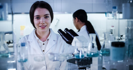 Multi ethnic science team working with microscope and computer. Female doctors in futuristic...