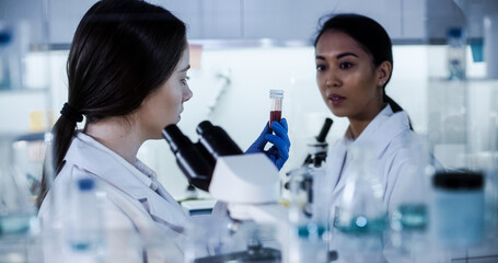 Multi ethnic science team working with microscope and computer. Female doctors in futuristic laboratory